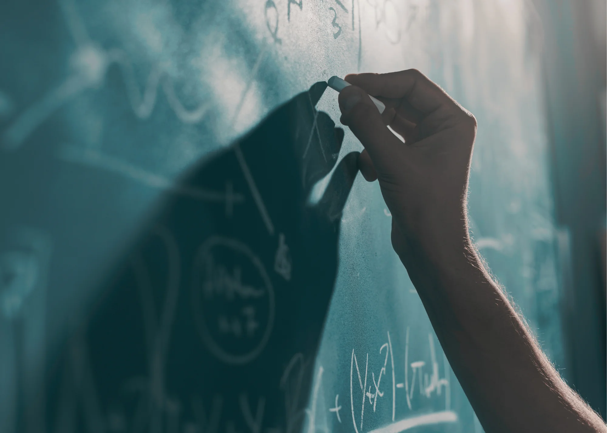 A close up of a person writing on a chalkboard to demonstrate WolfStrata's charitable support for education.